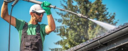 Man pressure washing a roof gutter.