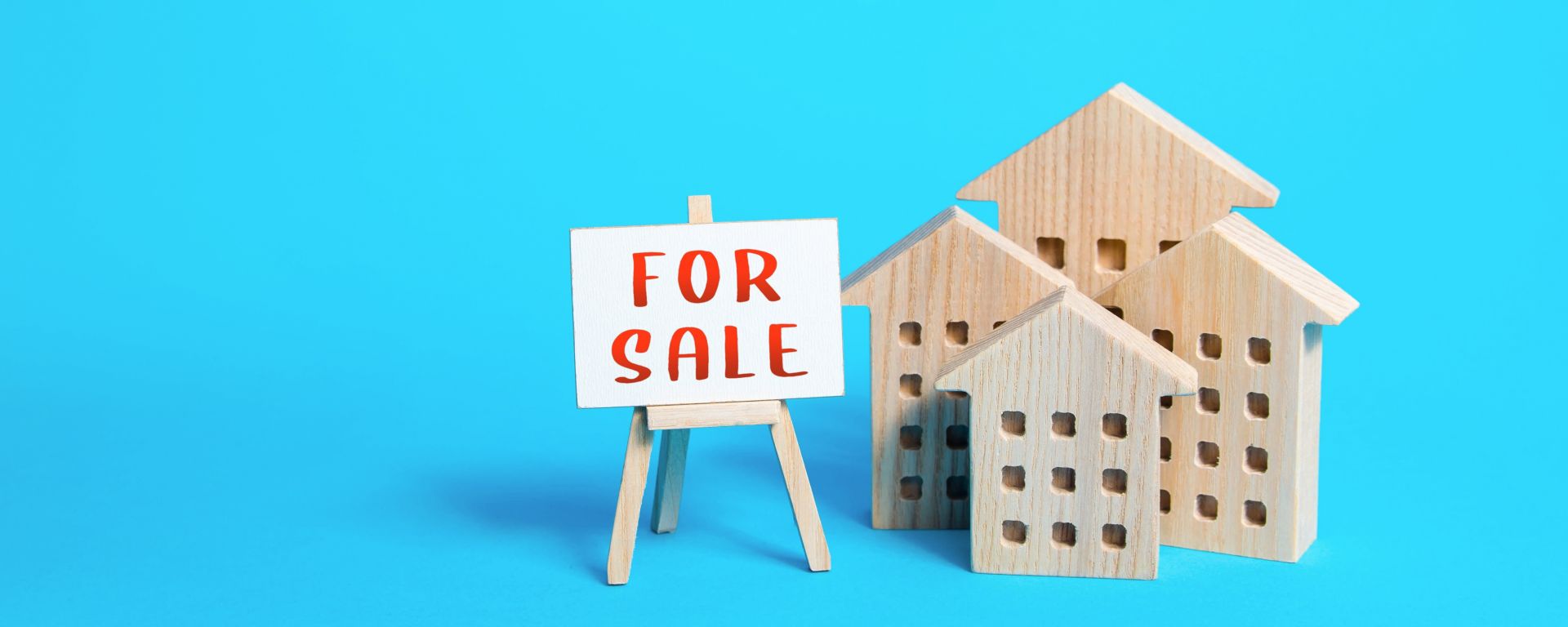 Small replicas of houses and 'For Sale' sign with a blue background.