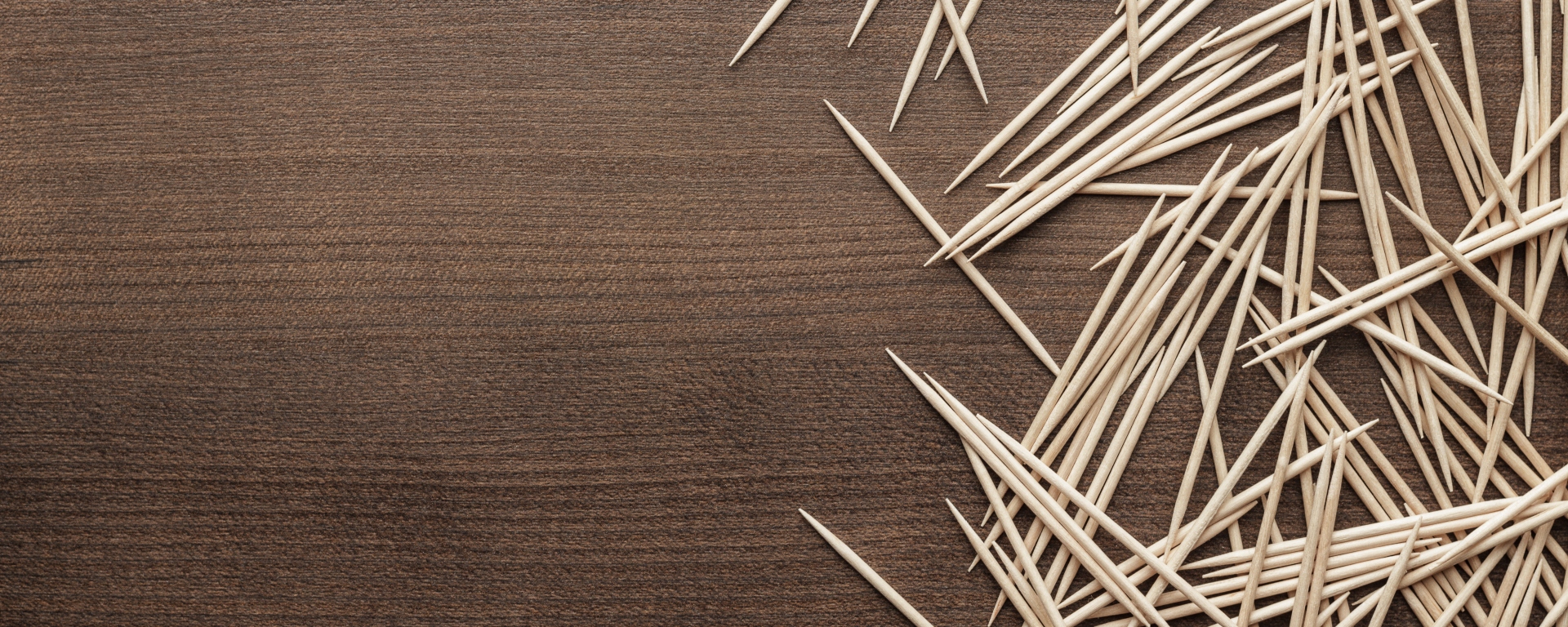 Many wooden toothpicks on a brown table background