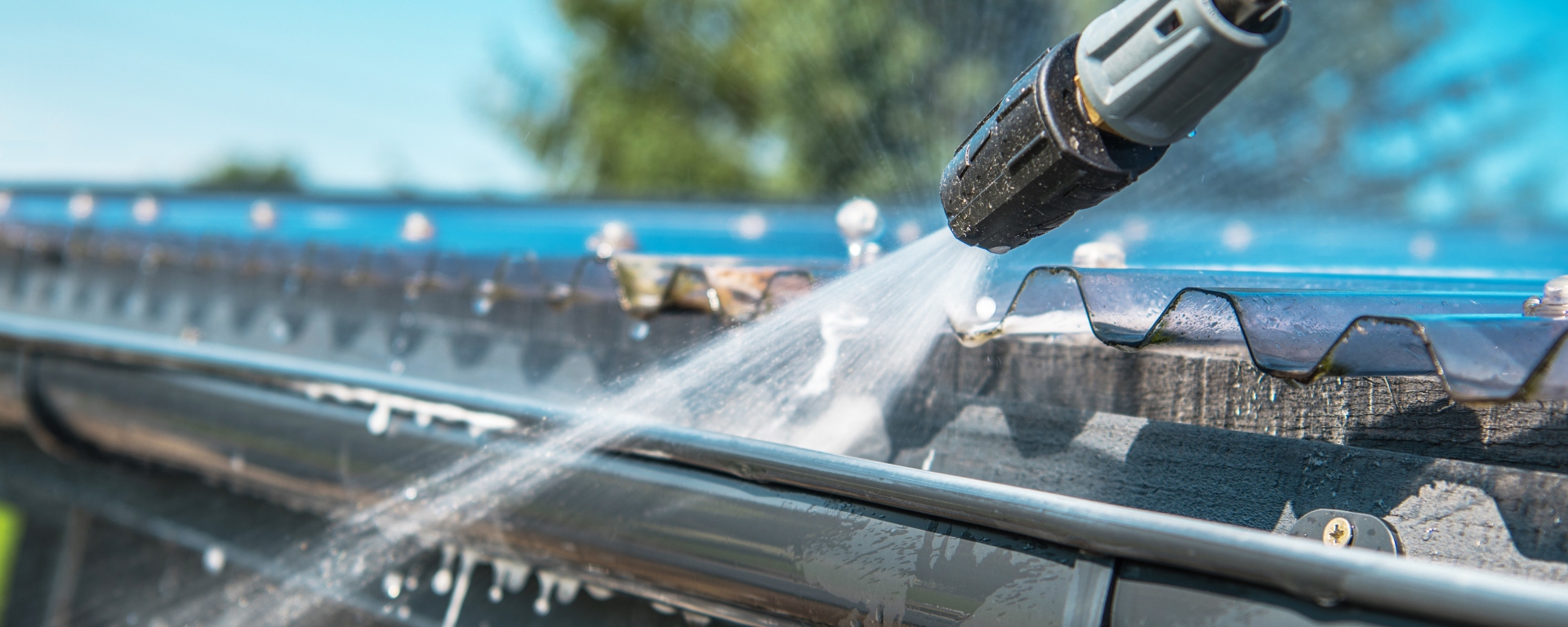 Pressure washer cleaning a roof gutter