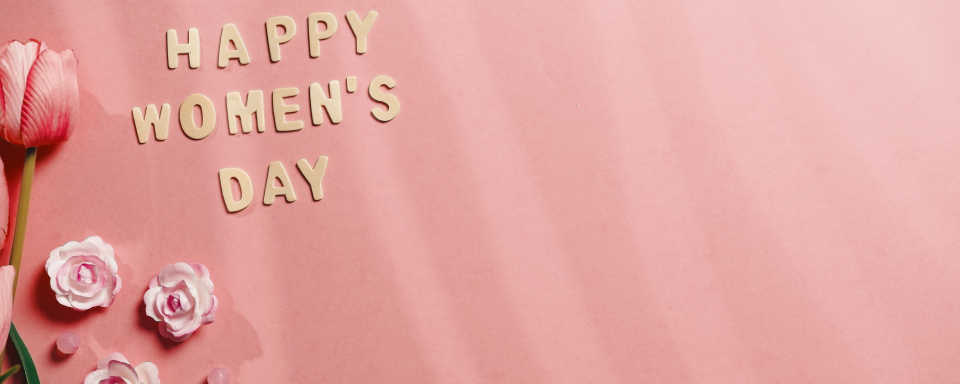 'Happy Women's Day' sign on pink background.