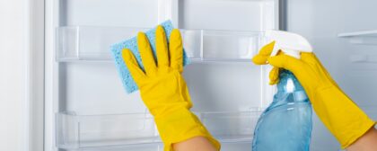 Close-up shot of a person's hands cleaning the inside of a fridge